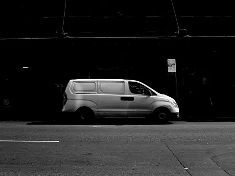 A plain white van parked on a dark street at night